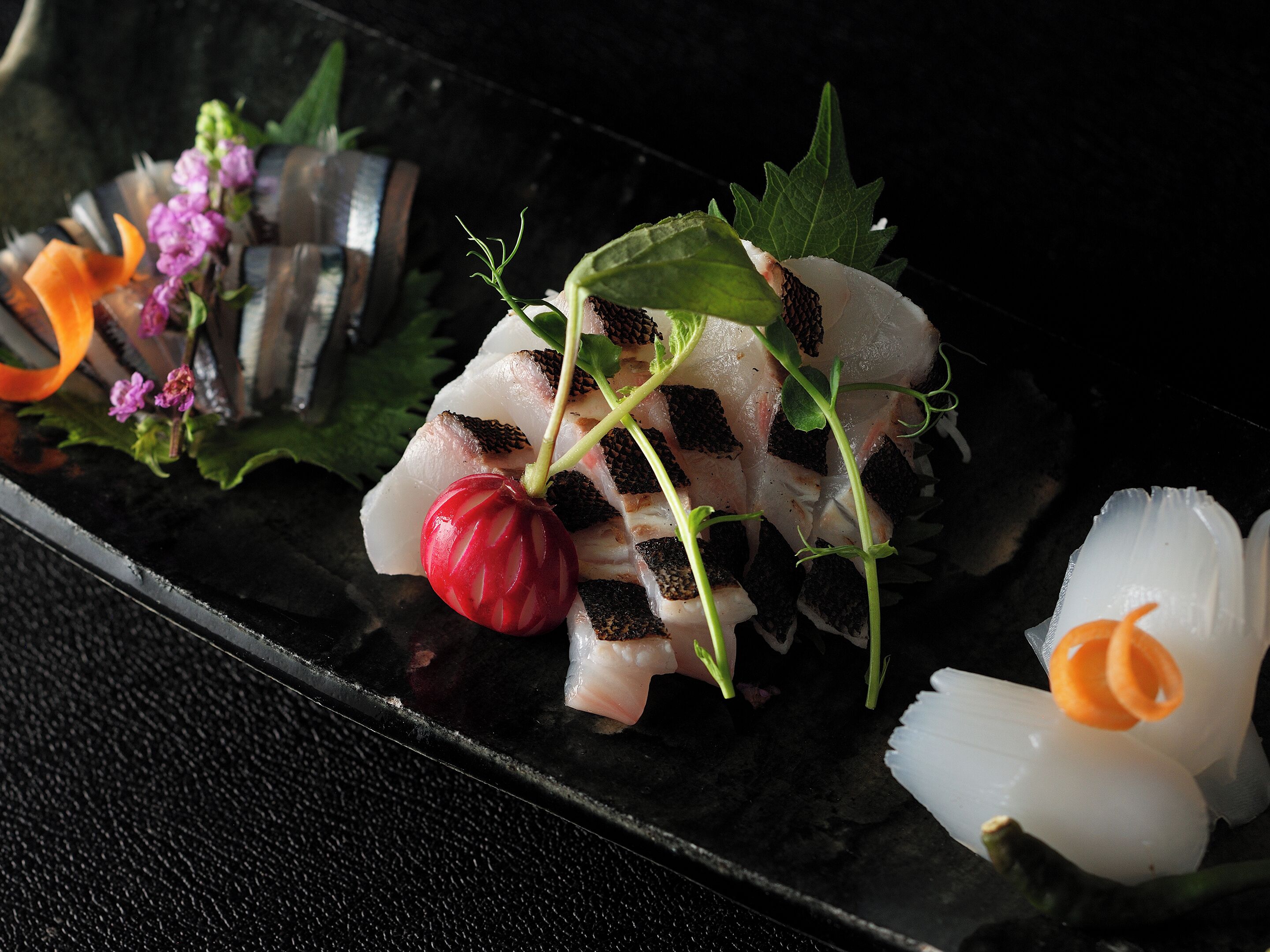 A dish with various ingredients including fish, greens, and a red radish.