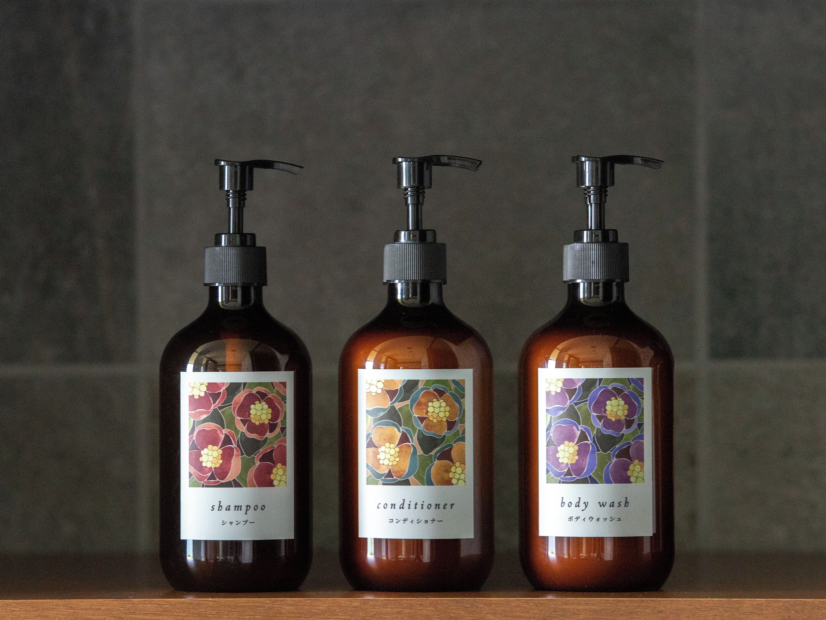 Tres botellas de líquido sobre un estante de madera frente a una pared con textura.