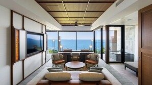 A modern lounge area with a sofa, chairs, and a coffee table, overlooking a scenic ocean view. - GOTO RETREAT by Onko Chishin (Goto)