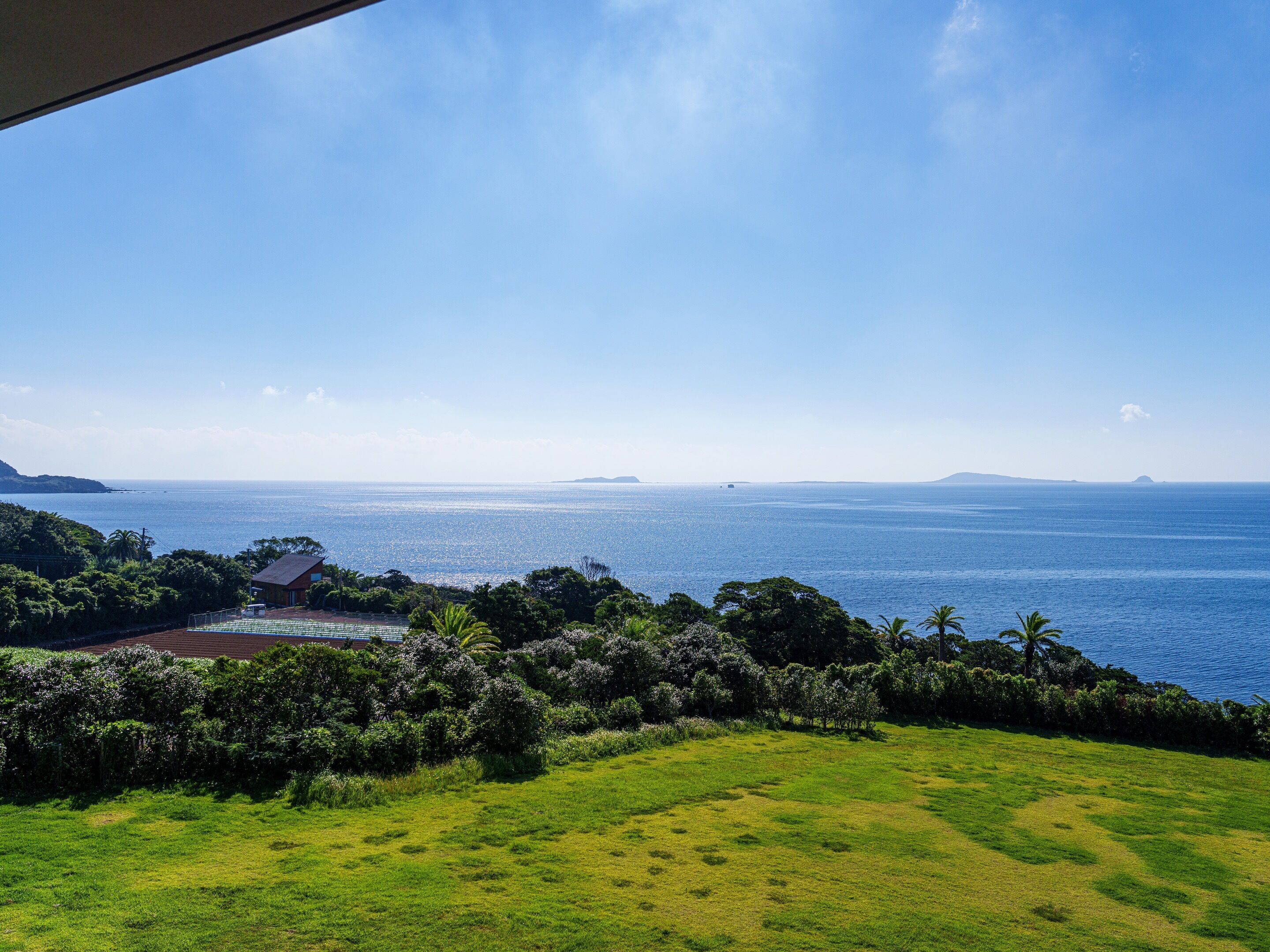 Un paysage côtier avec vue sur la mer, une zone herbeuse et un bâtiment doté d’un toit rouge.