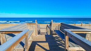 A wooden boardwalk leading to the beach with a clear view of the ocean.