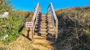 A wooden staircase leading up to a beach with a sign that reads "KEEP OFF THE DUNES".