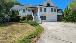 A two-story house with a front porch, a staircase leading to the entrance, and a garage.