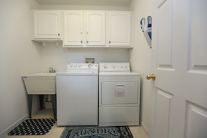 A compact laundry room with a washing machine, dryer, and a sink. - 24 By The Shore is beach living 24 hours a day- Private Pool! (Southern Shores)
