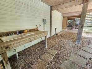 A rustic wooden bench with a sink and a broom leaning against it. - 24 By The Shore is beach living 24 hours a day- Private Pool! (Southern Shores)