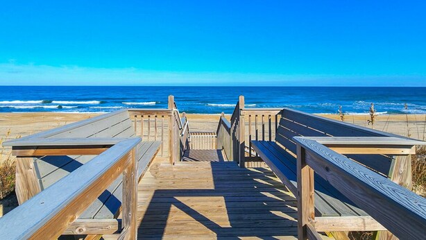A wooden boardwalk leading to the beach with a clear view of the ocean.