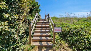 A wooden staircase leading up to a sandy area with a sign that reads "KEEP OFF THE DUNES."
