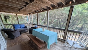 A covered outdoor seating area with a table, benches, and chairs.