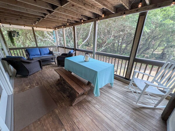 A covered outdoor seating area with a table, benches, and chairs.