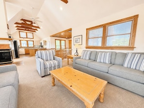 A spacious living room with a sofa, striped armchairs, a wooden coffee table, and a fireplace.