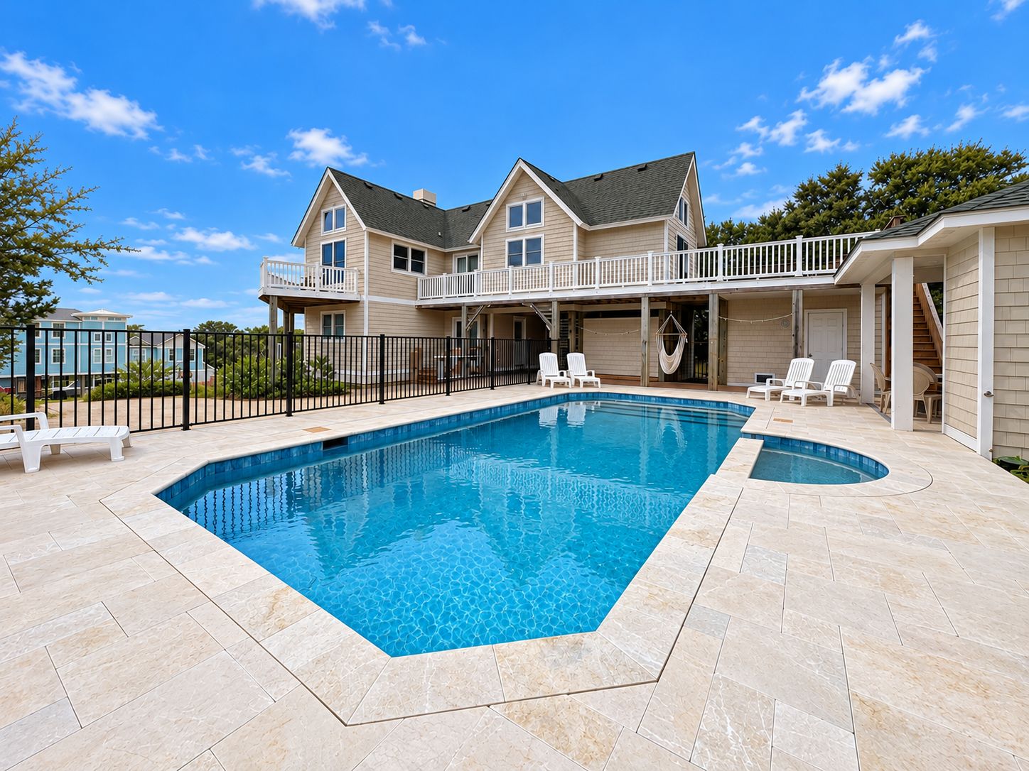 A two-story house with a swimming pool, outdoor seating, and a covered patio area.