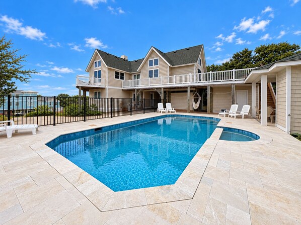 A two-story house with a swimming pool, outdoor seating, and a covered patio area.