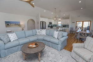A modern living room with a sectional sofa, a coffee table, and a dining area with a table and chairs.