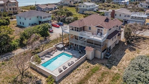 A two-story house with a swimming pool, multiple balconies, and a view of the ocean.