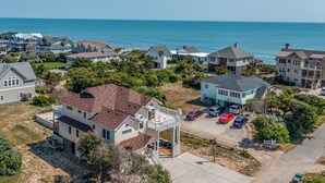 A residential area with houses, a parking lot, and a view of the ocean. - The Penny Swan - Wake up to beautiful ocean views from this oceanside 7BR home w/Private Pool! (Southern Shores)