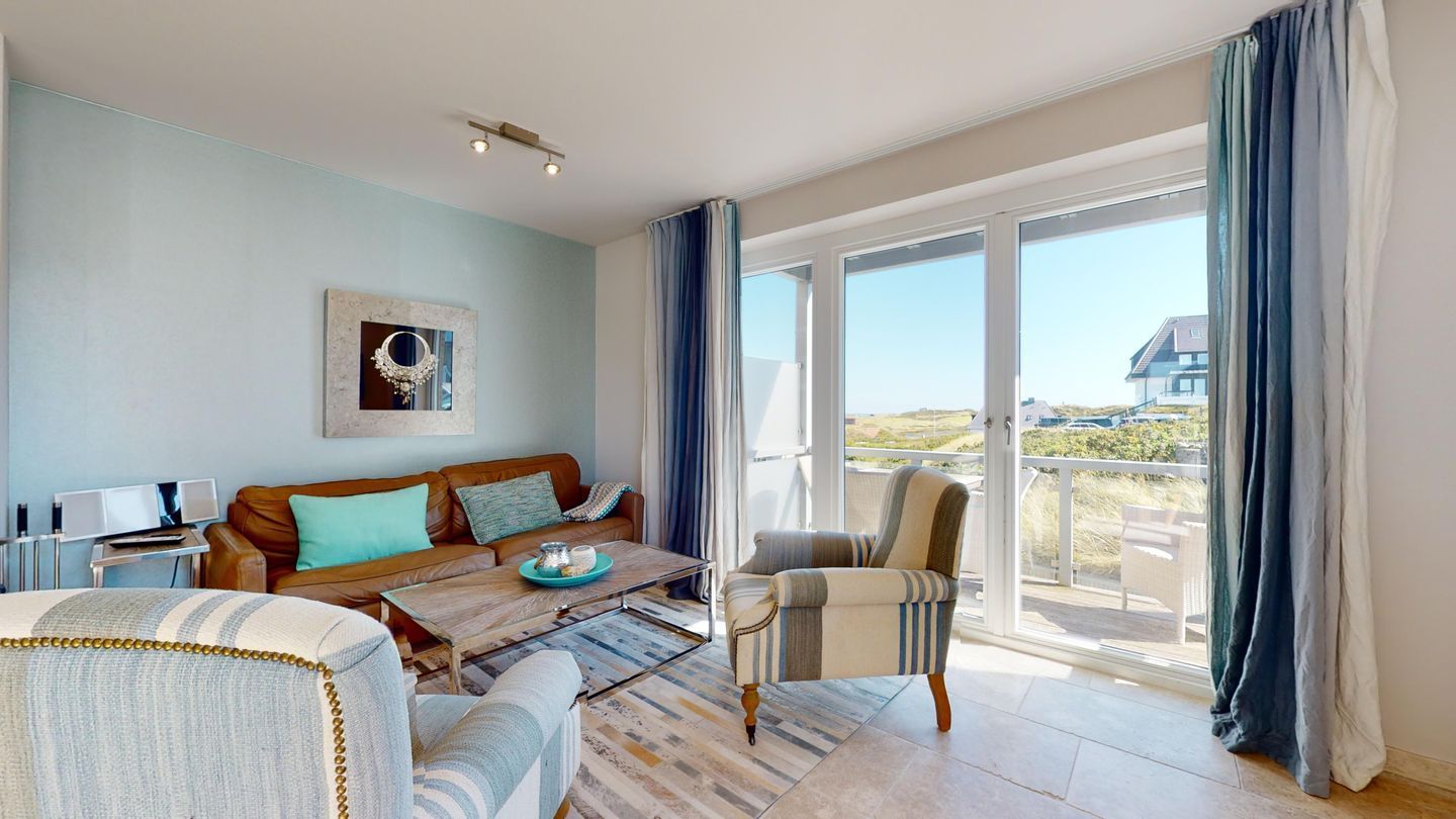 A spacious living room with a large window, a sofa, a coffee table, and a chair.
