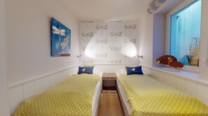 Une chambre avec deux lits, une fenêtre donnant sur un beau paysage, un mur décoré de motifs de papillons et un tableau.