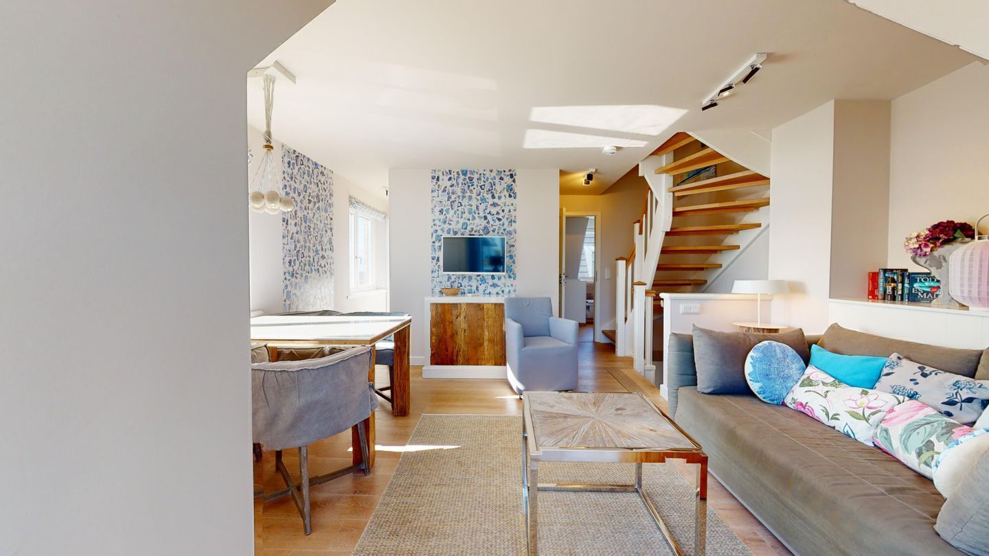 A modern living room with a sofa, coffee table, and a staircase leading to another level.