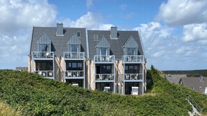 Un immeuble moderne à plusieurs étages, doté de balcons et de grandes fenêtres, situé sur une colline.