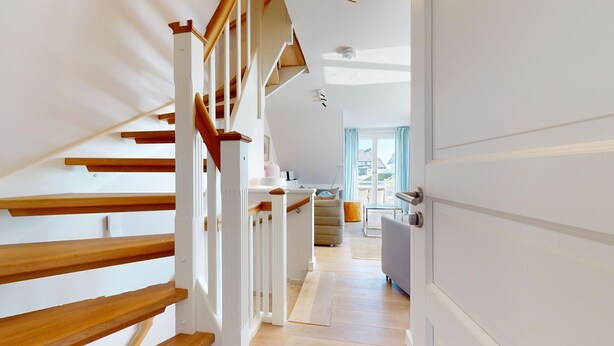 Un intérieur moderne avec un escalier en bois, un espace cuisine et une vue sur l’extérieur.