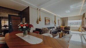 Ein modernes Wohnzimmer mit einem Holzesstisch, einer Sofagarnitur und einem großen Fenster mit Blick auf die Stadt.