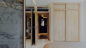Ein modernes Hotelzimmer mit Marmorwand, Holzschrank und Bett mit beige farbenem Überwurf.