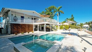 Una casa de dos pisos con piscina, un patio cubierto y vista al agua.