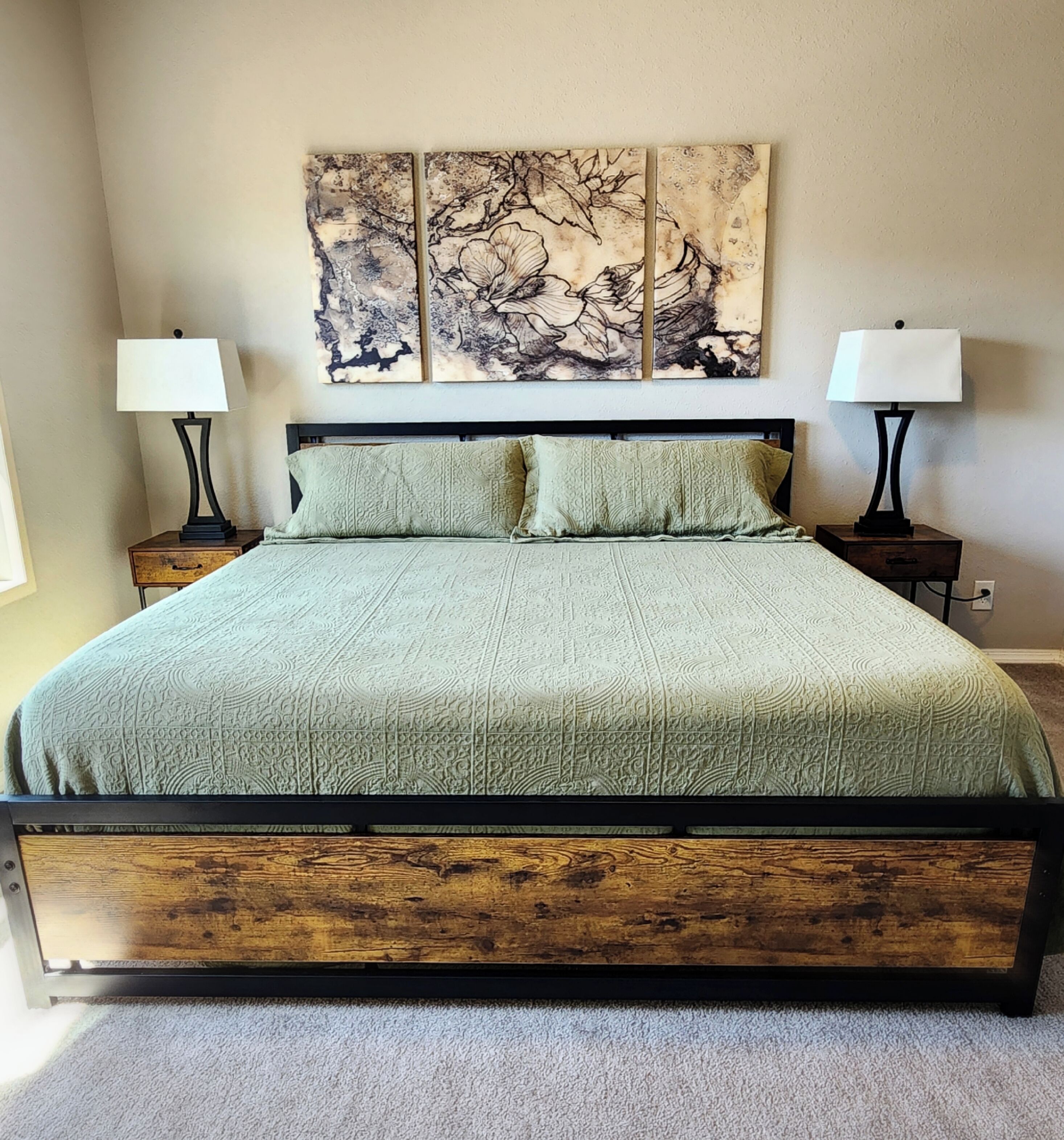 Une chambre à coucher avec un grand lit, deux tables de chevet et une œuvre d’art accrochée au mur.