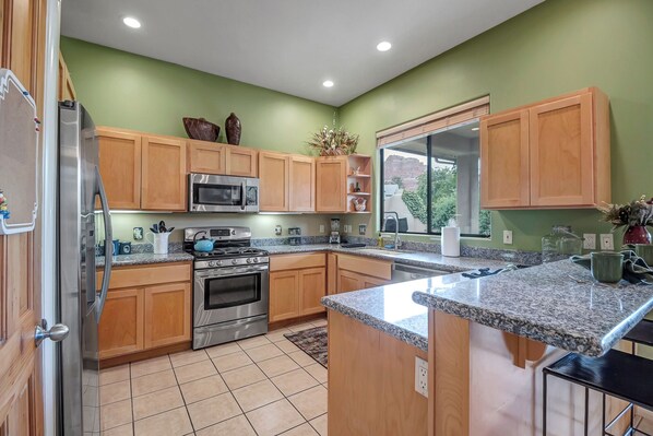 A kitchen with wooden cabinets, stainless steel appliances, and a granite countertop.