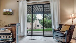 A room with a sliding glass door leading to a patio, a black leather chair, a lamp, and a television mounted on the wall. - Experience luxury at Sedona Garden Oasis at Bell Rock, perfect for families! (Sedona)