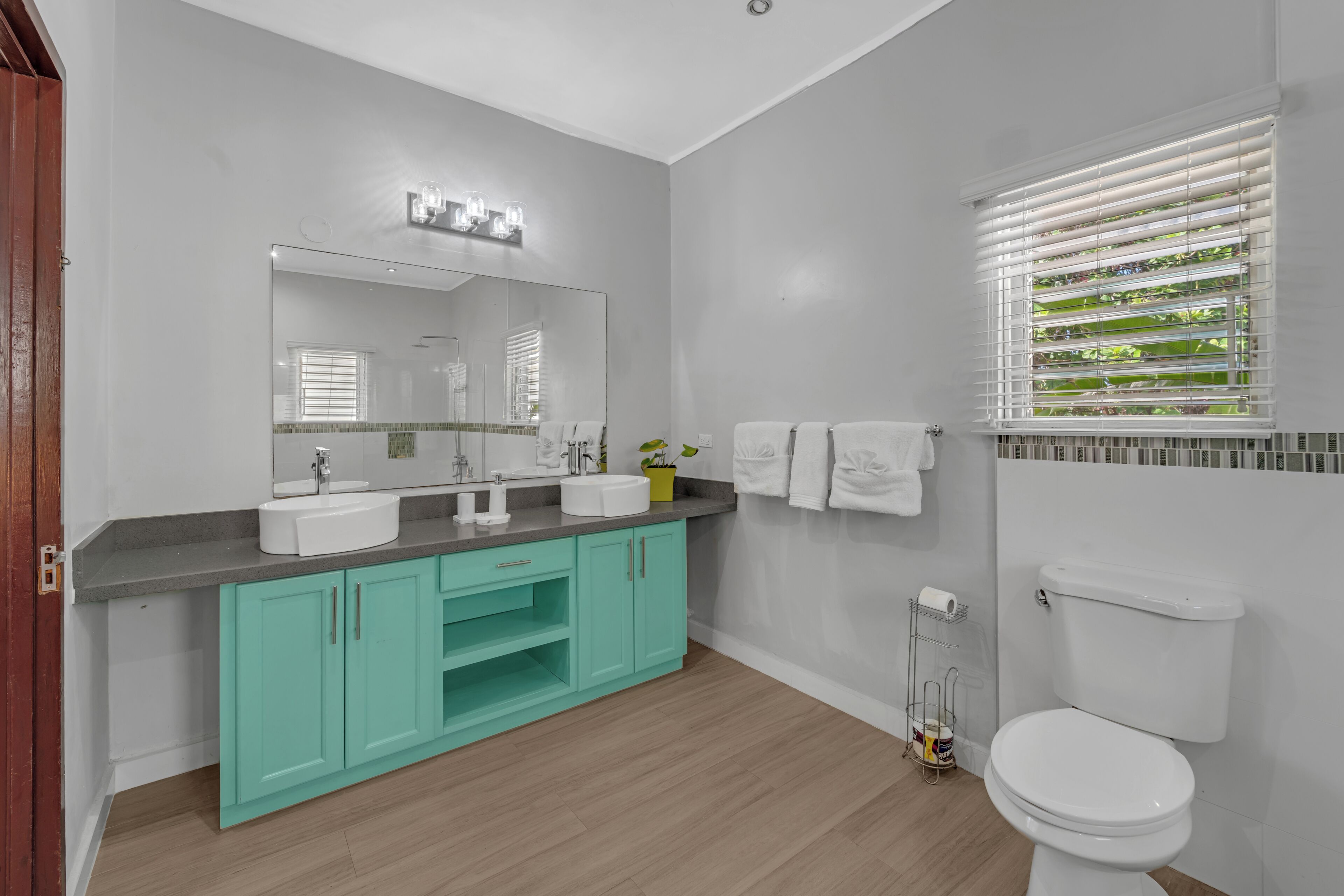Un baño moderno con un lavamanos blanco, muebles turquesa y un inodoro blanco.