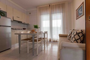 Eine moderne Küche mit weißen Schränken, einem Esstisch mit Stühlen und einem Sofa im Wohnbereich.