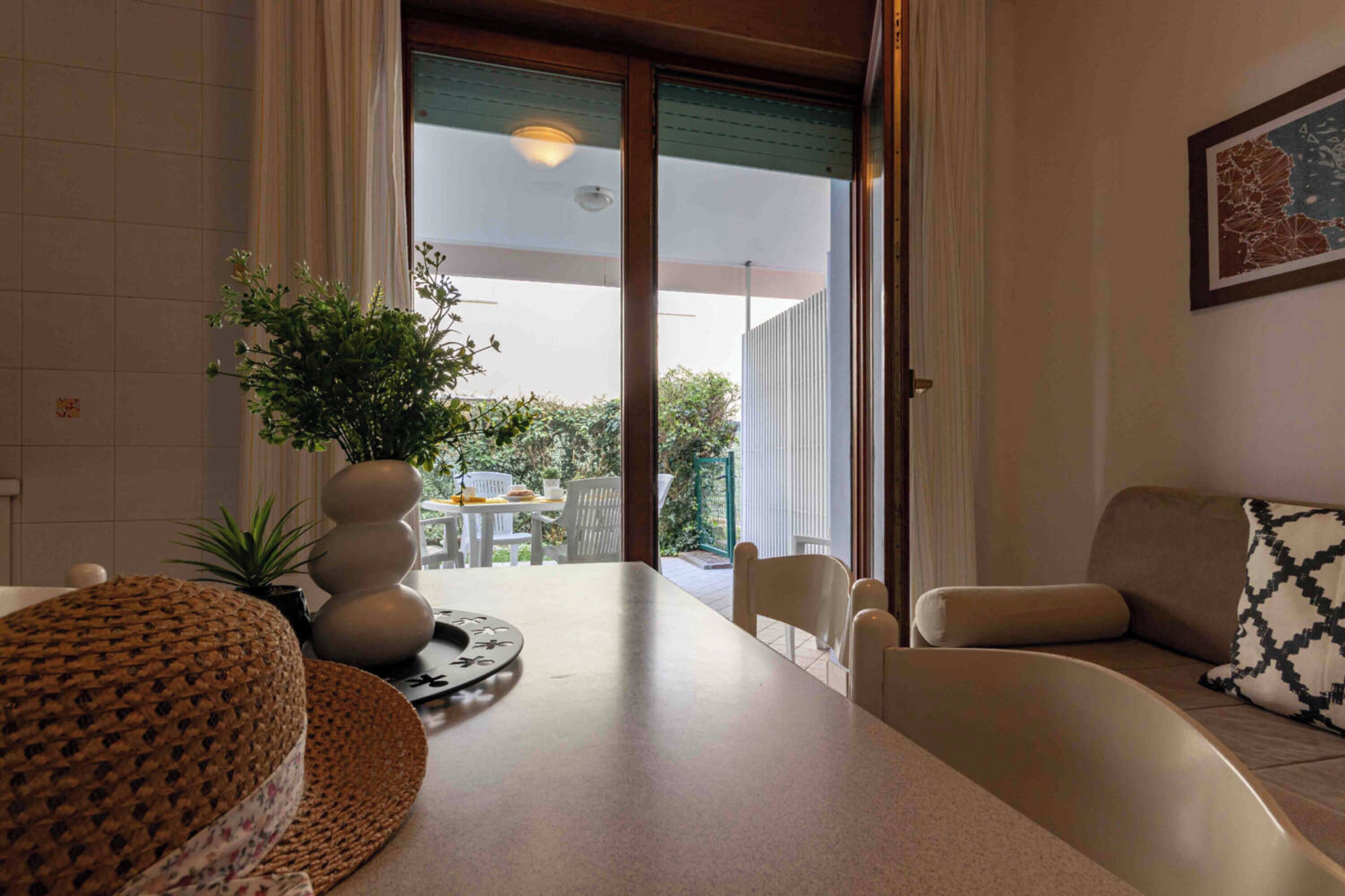 A modern living room with a sofa, a round woven table, and a potted plant.