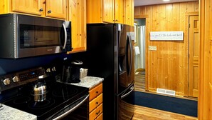 Eine Küche mit Holzschränken, einer Edelstahl-Mikrowelle, einem Kühlschrank und einem Herd.