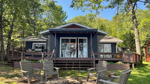Eine Hütte mit einer Terrasse, Sitzgelegenheiten im Freien und einer Feuerstelle.