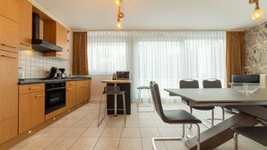 Una cocina moderna con armarios de madera, una estufa negra y un comedor con mesa y sillas.