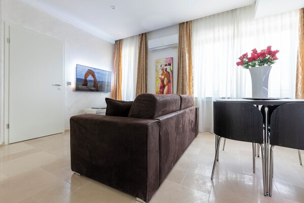 Una sala de estar moderna con un sofá marrón, una mesa de comedor negra y un jarrón con flores rojas.