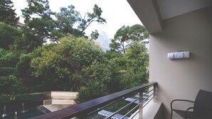 A balcony with a wooden bench, metal railing, and a chair. - Cosy Studio in Camps Bay (Cape Town)
