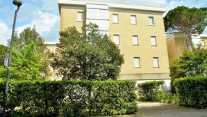 A multi-story residential building with a brick facade, multiple windows, and a paved driveway. - Lovely Flat Next to the Beach and the City Centre (San Michele al Tagliamento)