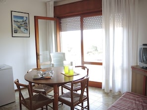 Un comedor con una mesa, sillas, un televisor y vistas a través de una ventana.