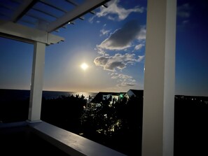 Ein Balkon mit Blick auf den Ozean und einen Sonnenuntergang.
