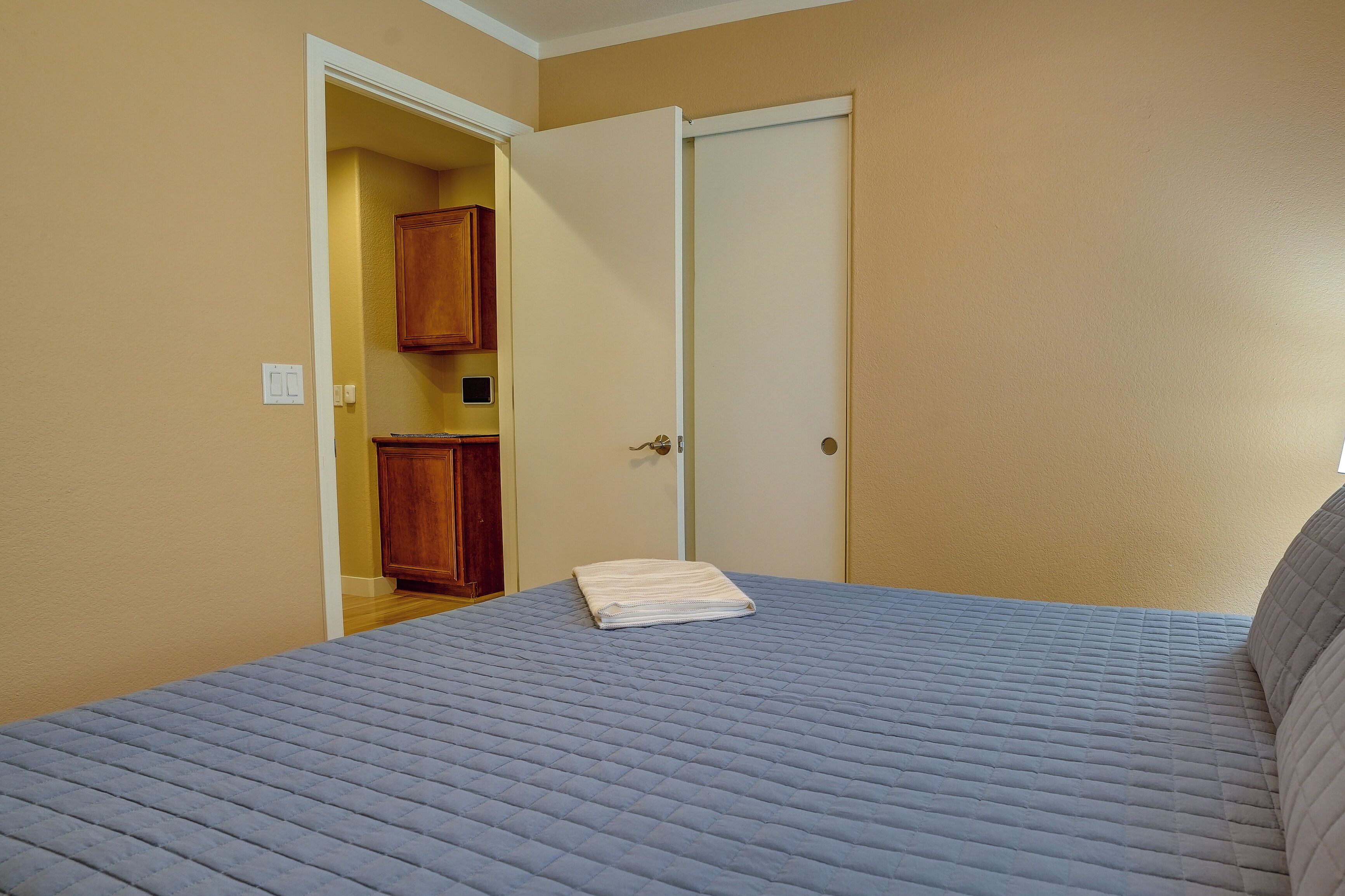 A bedroom with a bed, a door, and a wooden cabinet.