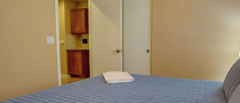 A bedroom with a bed, a door, and a wooden cabinet.
