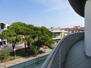 Un balcón con vista a una calle arbolada y edificios.