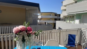 Een balkon met een gedekte tafel, een bloevas en een blauwe tafelkleed.