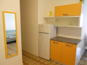A compact kitchen with a refrigerator, a sink, and a countertop. - Bright Flat With a Furnished Outdoor Space (San Michele al Tagliamento)