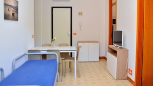 A small, clean room with a bed, a desk, a chair, a TV, and a cabinet. - Spacious and Bright Flat Near the Beach (San Michele al Tagliamento)