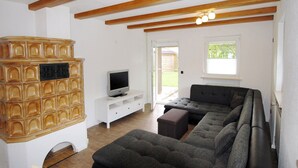 A modern living room with a sectional sofa, a television, and a wooden cabinet. - Ferienwohnung bis 3 Personen, auf 2 Ebenen, 80 qm, Balkon und Terrasse (Taching am See)