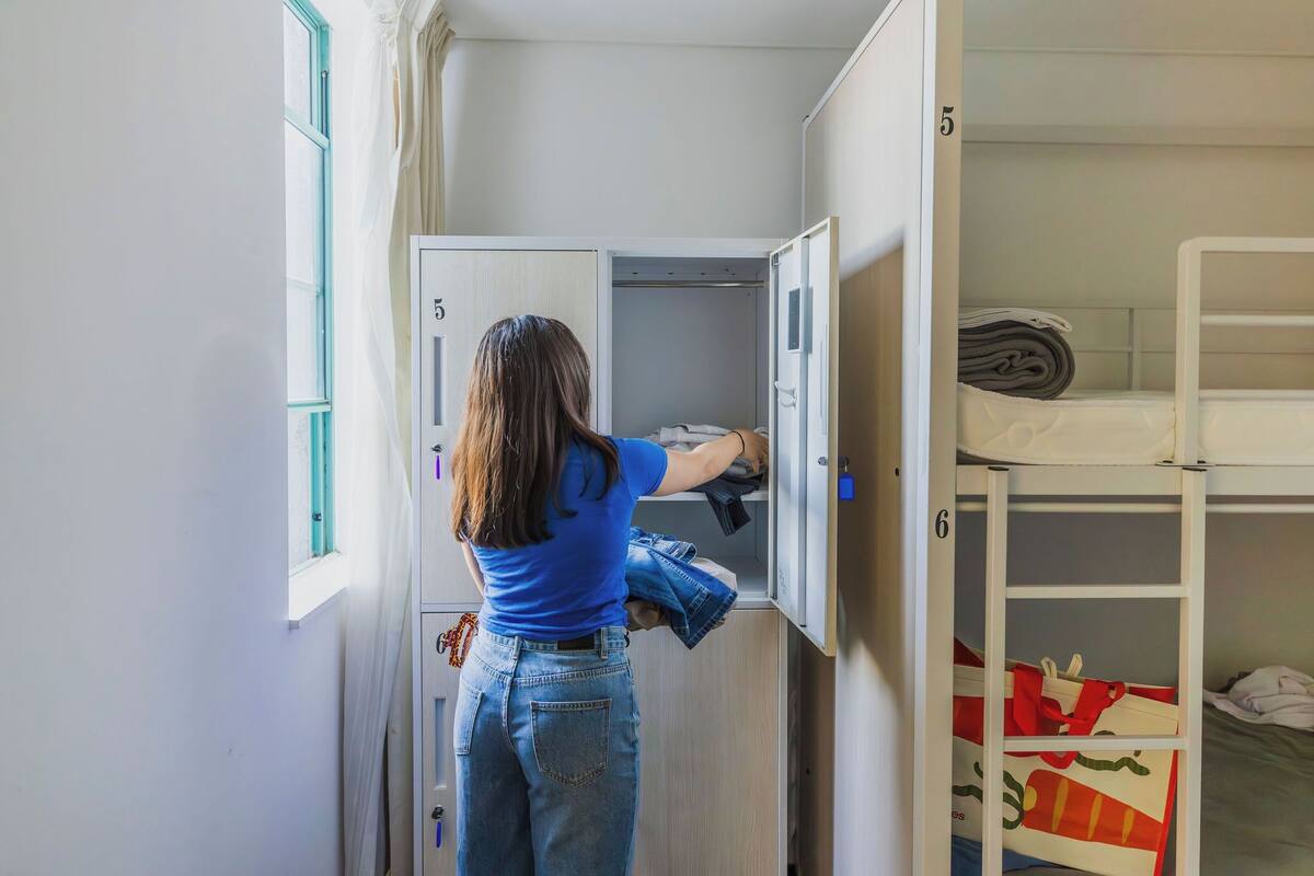 A room with a bunk bed, a wardrobe with numbered compartments, and a window with curtains.