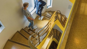 Un interior moderno con una escalera de caracol que presenta detalles en amarillo y una barandilla de vidrio.
